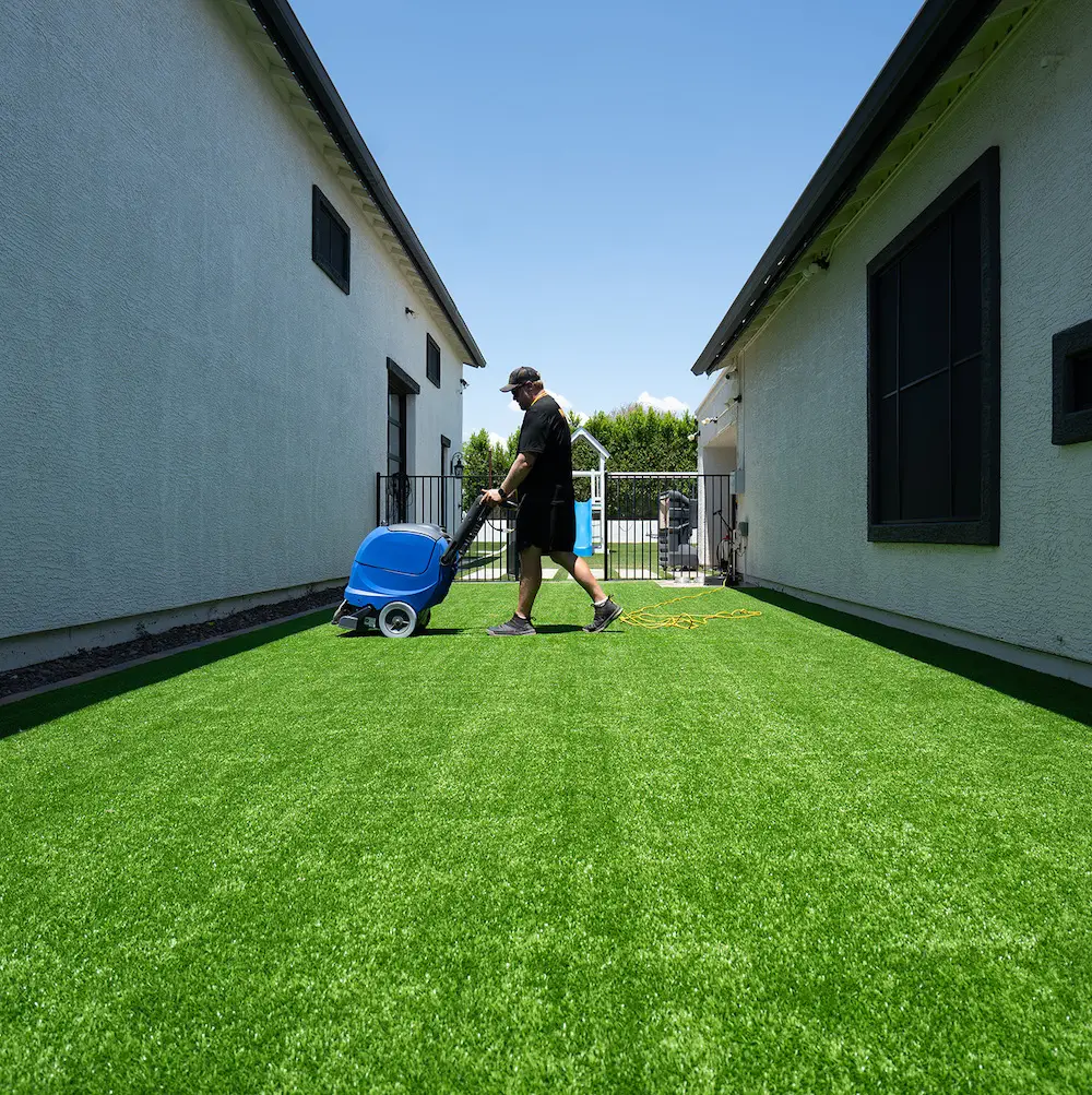 Squeaky Clean technician cleaning artificial turf between two buildings